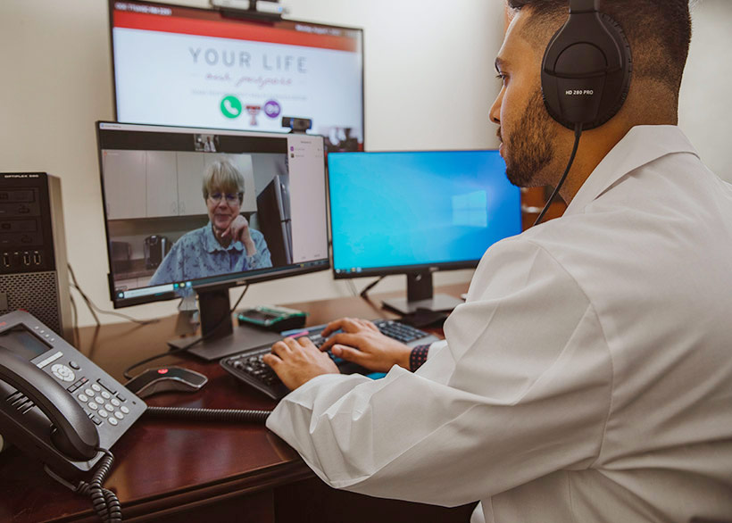Provider facing a computer talking to a patient for a Telehealth visit