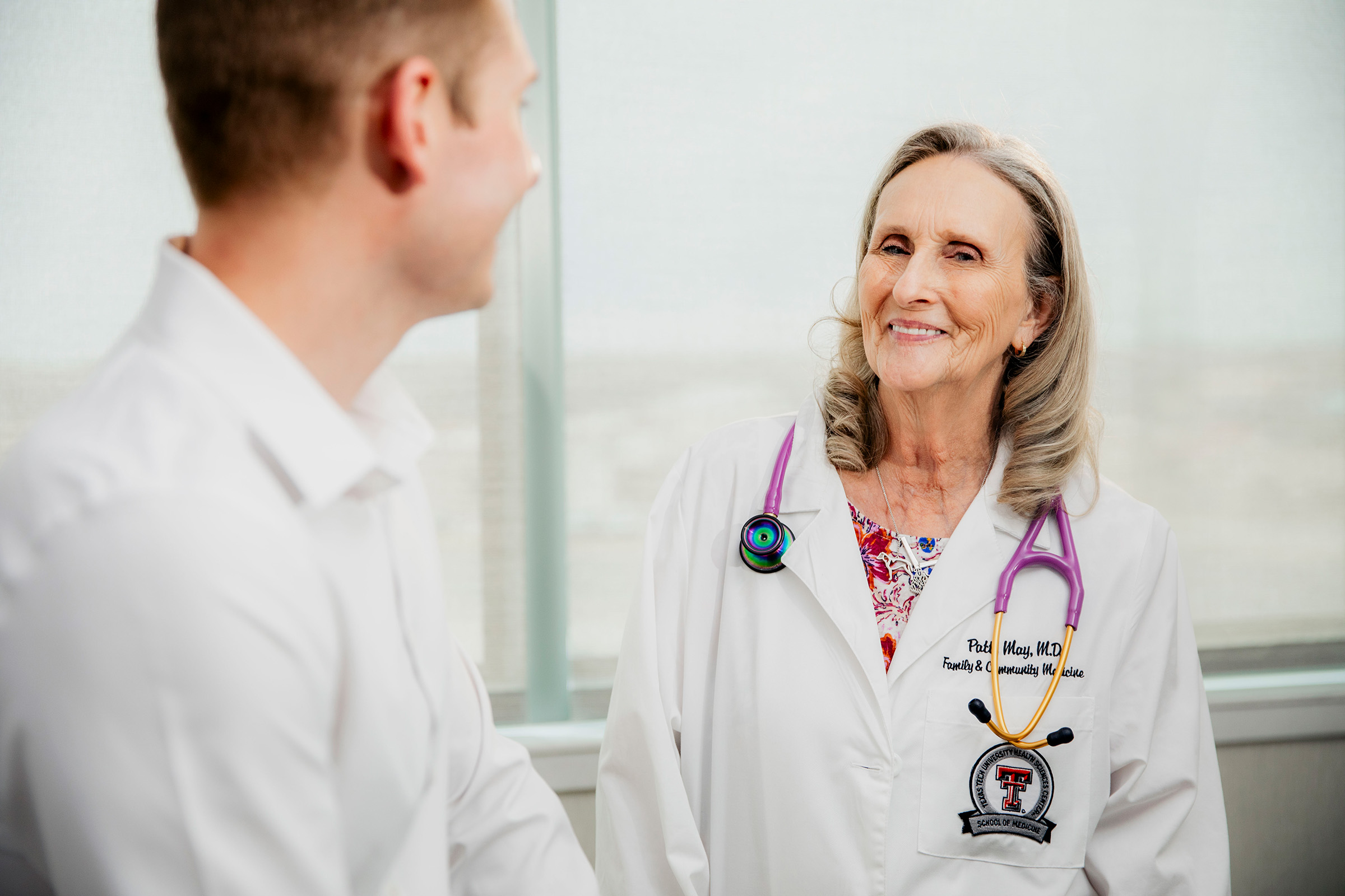 Doctor smiling at male patient in an exam room.