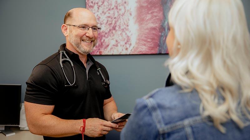 Physician standing holding pamphlet smiling at patient