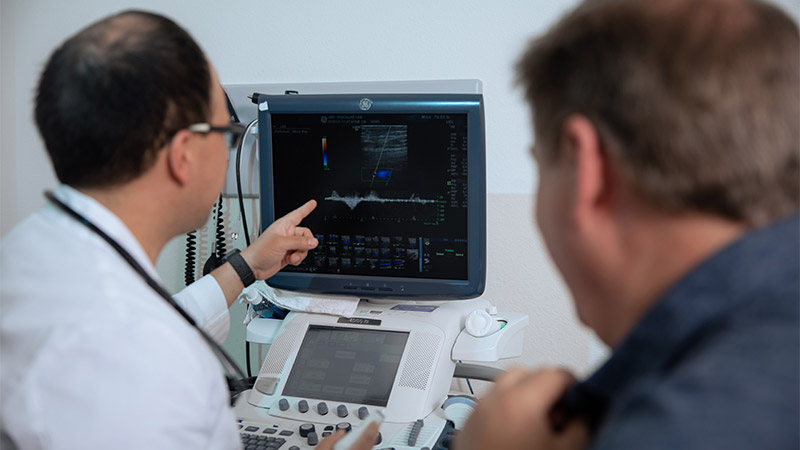 Provider pointing and  looking at sonography screen with patient
