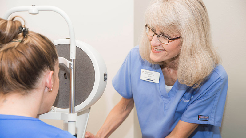 Staff member assisting patient in vision machine.