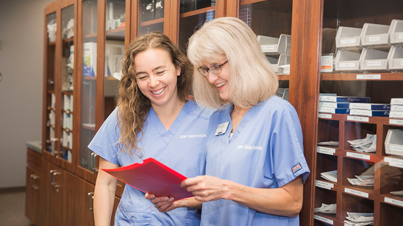 Two employees in scrubs looking at file 